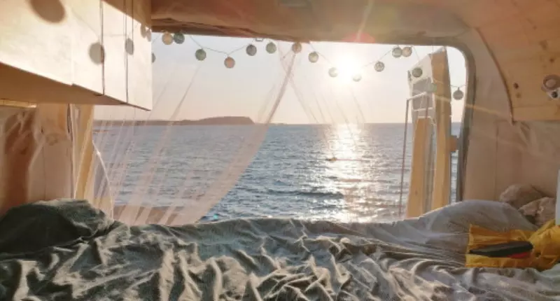 Blick aus der Camper-Hecktür auf das Meer bei Sonnenuntergang. Gemütlichkeit im Wohnmobill