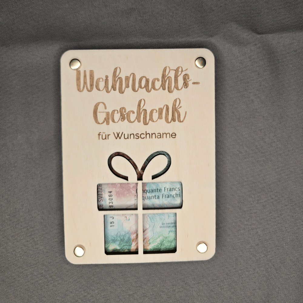Geld verpacken zu Weihnachten: Holzkarte mit Geschenkform liegt auf einem Geldschein, dazu Befestigungsmaterial